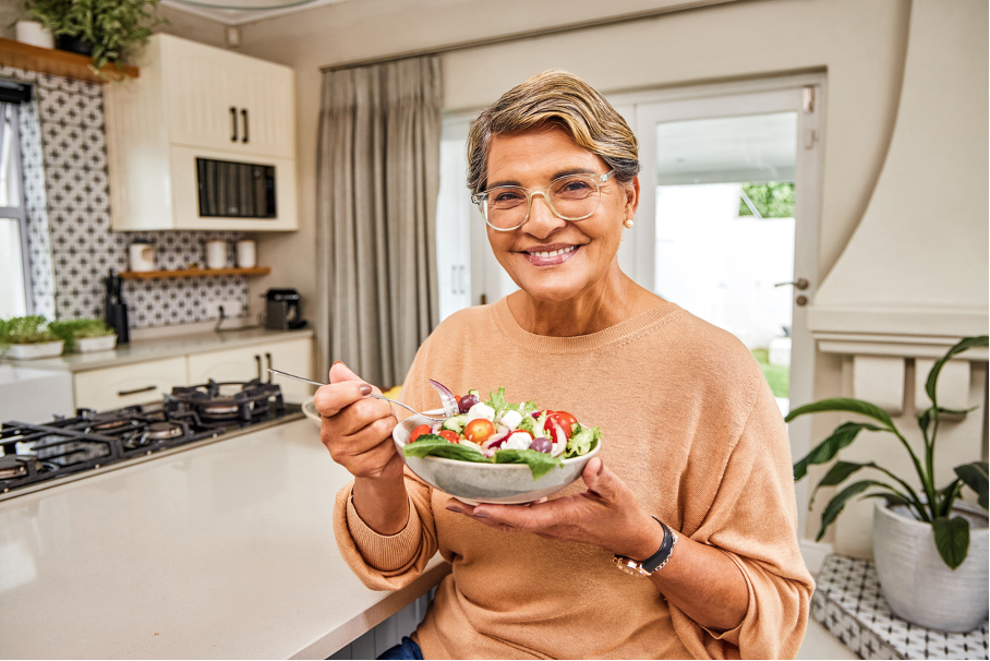 Starsza kobieta na diecie wegetariańskiej je sałatkę warzywną bogatą w witaminy b12 i witaminę c